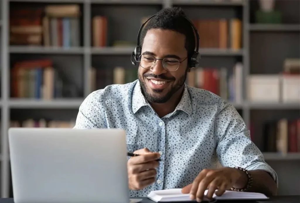 A man in a headset focused on his laptop, engaged in a business growth webinar online.