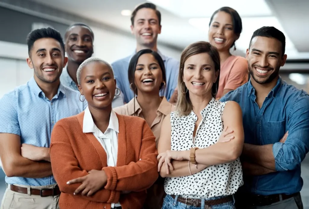 A diverse group of smiling individuals standing together, representing community and support in small business digital resources.